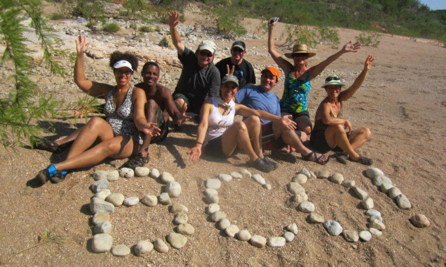 A group of BCO members having fun on the beach with BCO spelled out with rocks